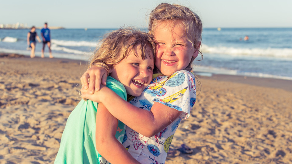 Zwei Kinder spielen am Strand, doch was tun bei Zahnbeschwerden im Urlaub?
