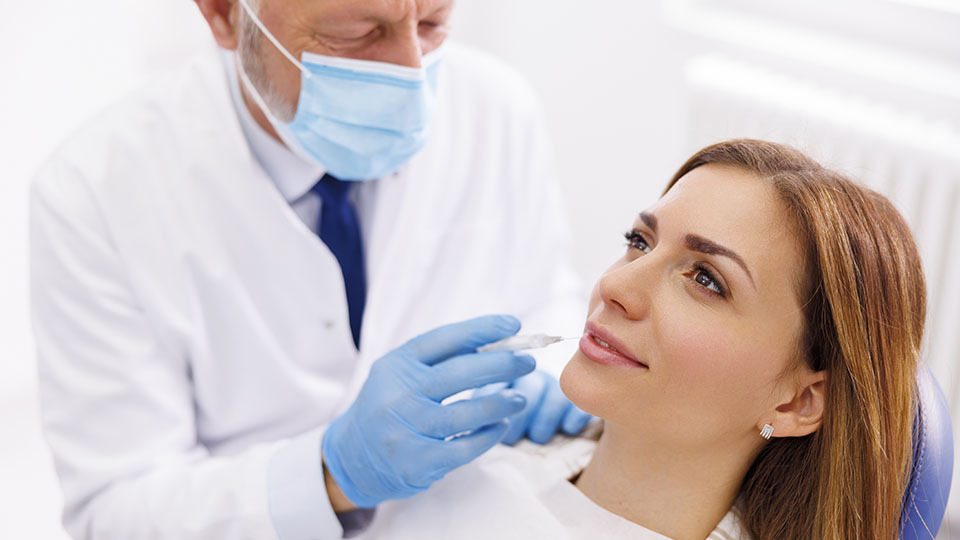Frau beim Zahnarzt erhält lokale Betäugung statt Vollnarkose.