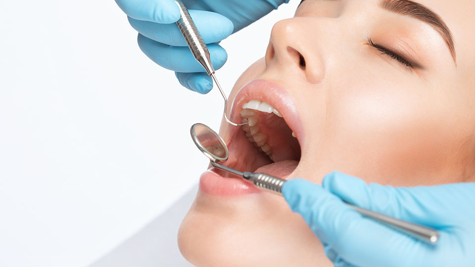 Karies behandeln: Frau, deren Zähne gerade auf Karies untersucht werden