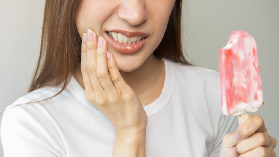 Eine Eis essende Frau mit schmerzenden Zähnen