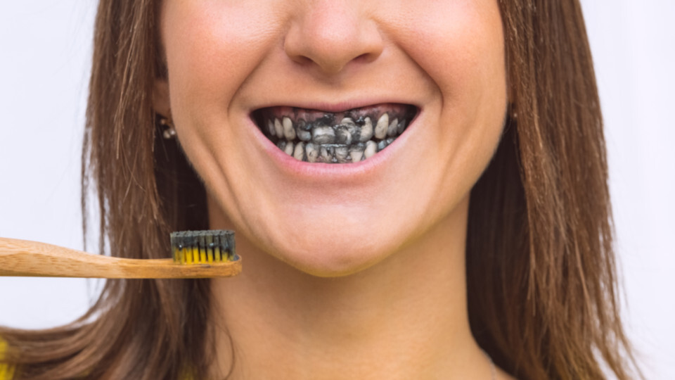 Eine Frau putzt sich die Zähne mit Zahnpasta mit Aktivkohle