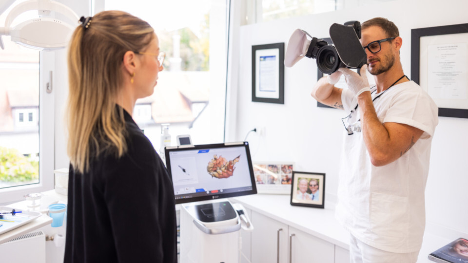 Der Zahnarzt in Regensburg macht ein Foto einer Patientin für eine digitale Anwendung