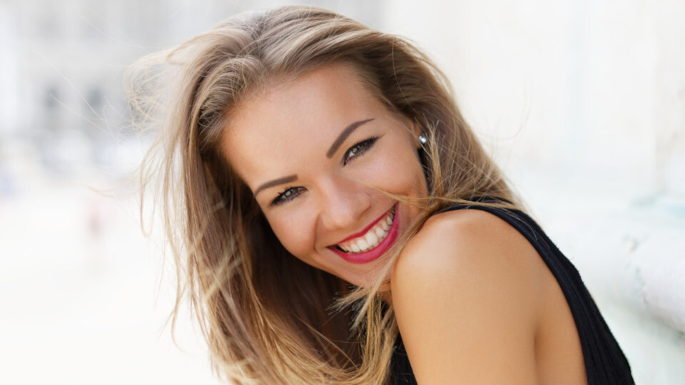Eine Frau mit Veneers oder Bleaching lächelt in die Kamera