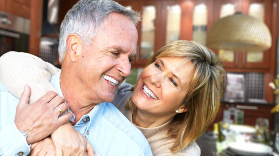 Ein lachendes älteres Ehepaar mit gesunden Zähnen dank guter Zahnpflege