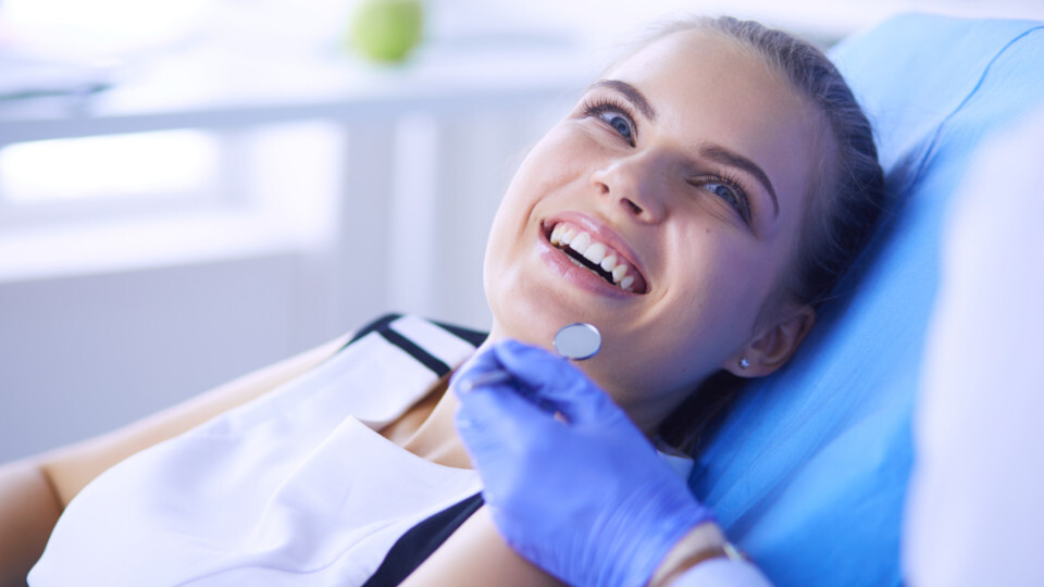 Eine lächelnde Frau auf einem Zahnarztstuhl