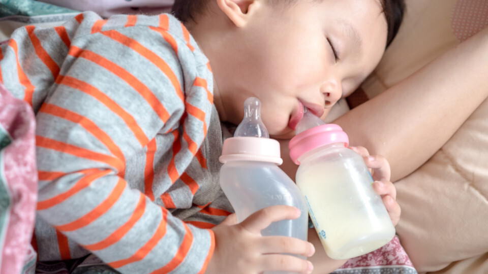 Ein Kleinkind schläft mit zwei Nuckelflaschen