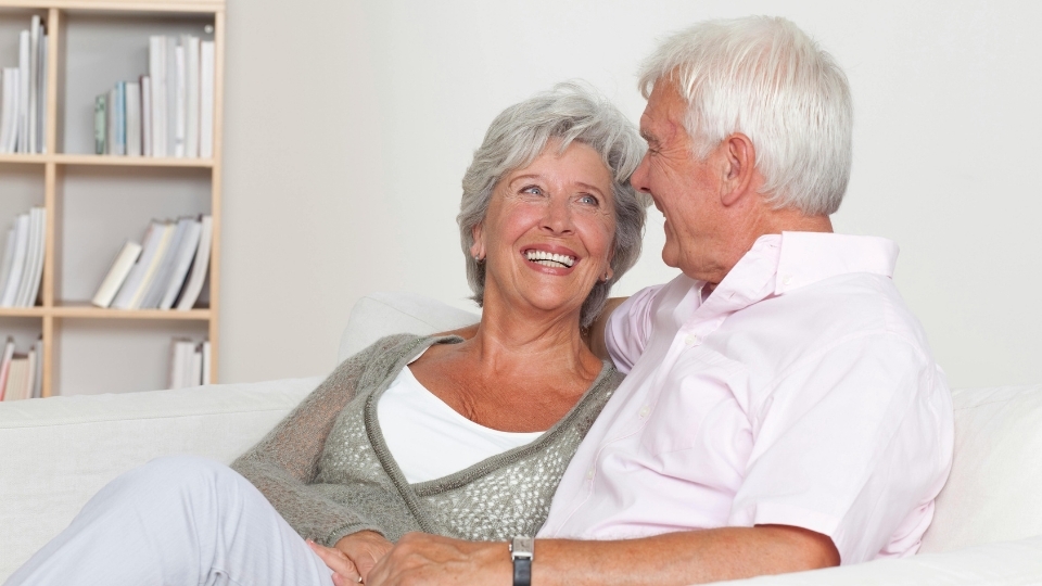Ein glückliches Ehepaar sitzt auf der Couch und freut sich über ihre "Festen Zähne an einem Tag"