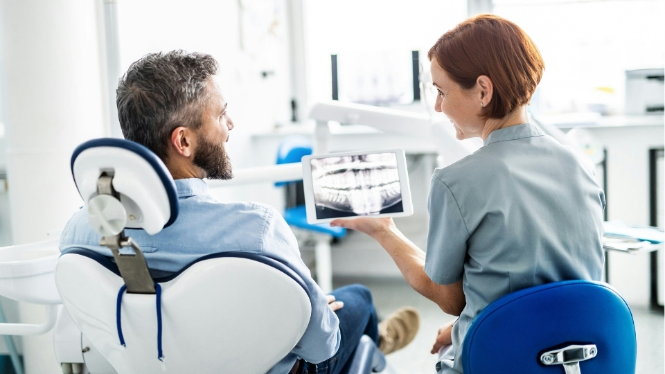 Eine Zahnärztin erklärt einem Patienten ein Röntgenbild